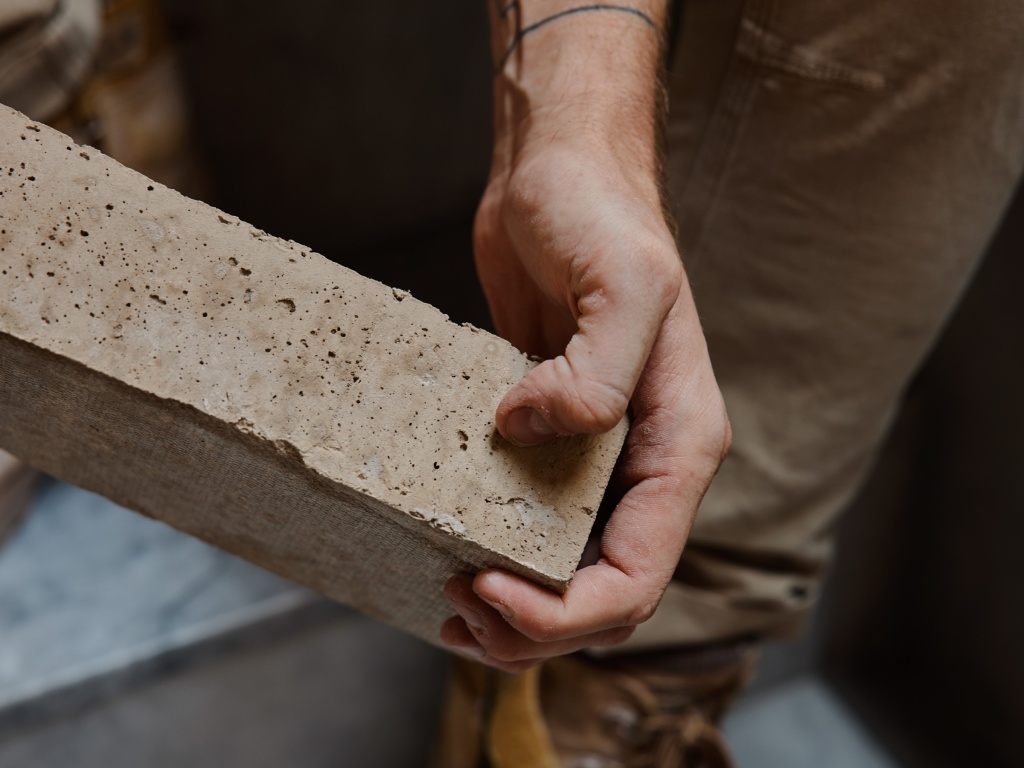 Detail of hands holding a brick.